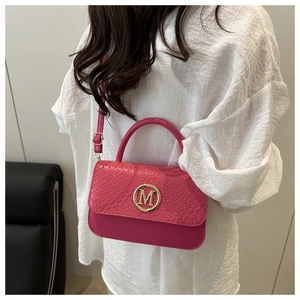Détail du sac à main rose avec texture motif serpent et fermoir logo M doré