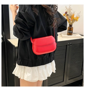 Chic red faux leather crossbody bag worn by model in a stylish indoor lifestyle setting