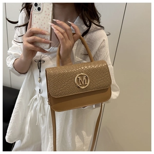 Mirror selfie showing the tan woven handbag with a golden M logo for daily style