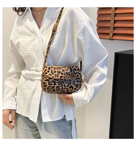 Detailed view of leopard print saddle bag styled with white shirt and denim jeans