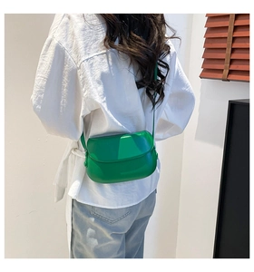 Green faux leather saddle bag worn by a model against a minimalist background
