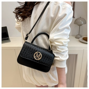 Detail of black leather crossbody bag with woven texture flap and golden M buckle