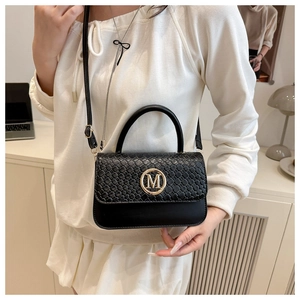 Détail du sac à main noir tressé avec logo M doré et bandoulière réglable pratique
