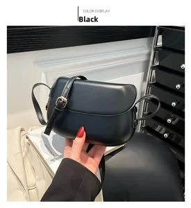 Detail view of the sleek black saddle bag with adjustable leather strap and gold buckle