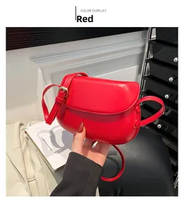 Detail view of mini red leather saddle bag with adjustable strap and golden metal buckle