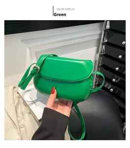 Detail view of the green leather saddle bag featuring gold hardware and adjustable strap