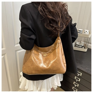 Rear view of brown hobo bag on shoulder showing soft leather texture and golden logo