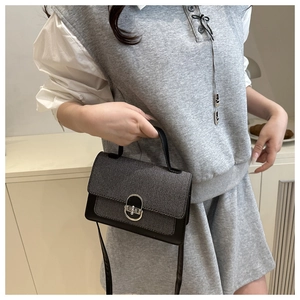Close-up of contrast crossbody bag with silver oval lock on a stylish fashion model