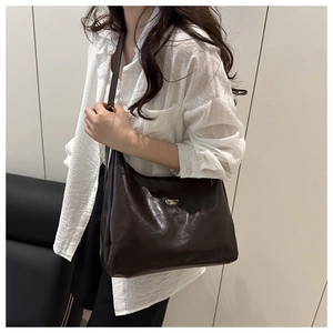 Detail of dark brown polished leather shoulder bag with oval FASHION BAGS metal emblem
