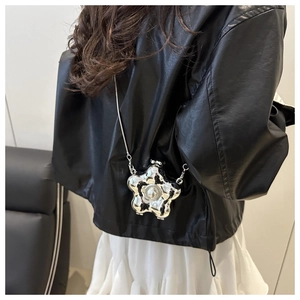 Detail einer silbernen Blumen-Umhängetasche mit Perle und metallischer Kette