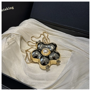 Macro detail of acrylic floral mini bag with golden edges, pearl center and snake chain