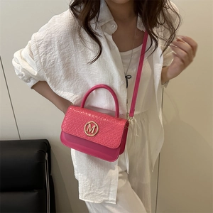 Pink crossbody square bag with gold M logo and croc-embossed texture shown on model