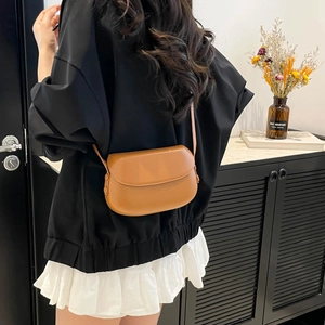 Minimalist brown saddle crossbody bag for women shown on model in a modern lifestyle setting