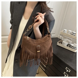Close-up of vintage dark brown suede shoulder bag with long fringe tassels and metal buckle