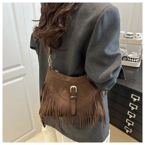 Détail du sac à bandoulière en daim marron avec boucle en métal et franges bohèmes rétro