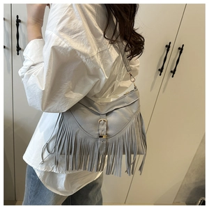 Vue détaillée du sac à bandoulière gris clair avec pompons bohèmes et boucle dorée