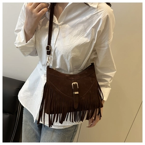 Détail d'un sac à bandoulière en daim marron foncé avec de longues franges et boucle