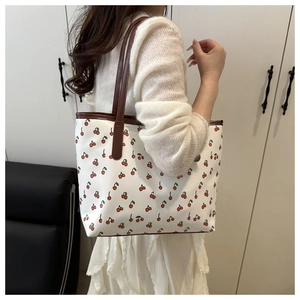 Side view of floral tote bag with cherry print shown on shoulder for size reference