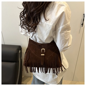 Détail d'un sac cabas en daim marron foncé avec des franges bohèmes et une boucle en métal