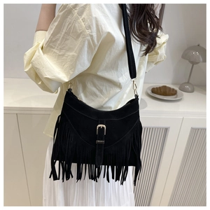 Detail of black suede tote bag with fringe tassels and gold metallic buckle on the strap