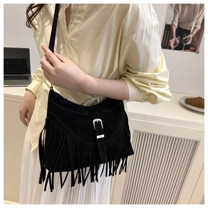 Detail of black suede hobo bag with bohemian fringe and decorative buckle strap