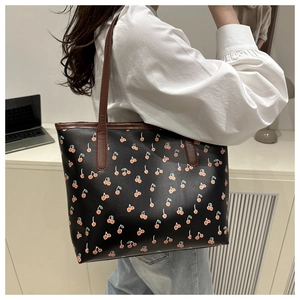 Detailed side view of large floral tote bag with cherry print and brown leather straps