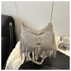 Close-up of gray suede tote bag featuring long fringes and decorative metal buckle strap