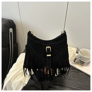 Close-up of black suede crescent bag featuring long fringes and a gold metal buckle detail