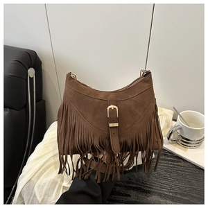 Detail of brown suede crescent bag with bohemian tassels and gold horseshoe buckle