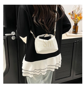 Détail du sac bandoulière en cuir blanc avec lettrage SM en clous dorés et boucles en métal