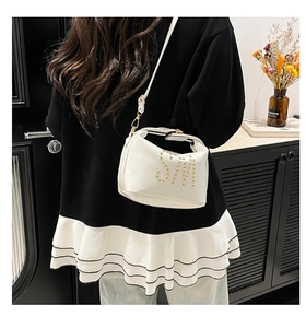Détail d'un sac cabas en similicuir blanc avec clous dorés motif SM et bandoulière