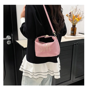 Sac cabas en cuir verni rose avec logo SM en rivets dorés porté par un mannequin