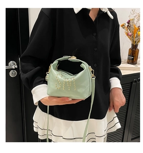 Détail du sac fourre-tout vert menthe à rivets dorés porté par un mannequin chic