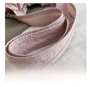 Dettaglio della tracolla in nylon rosa con doppia cucitura bianca e trama stropicciata