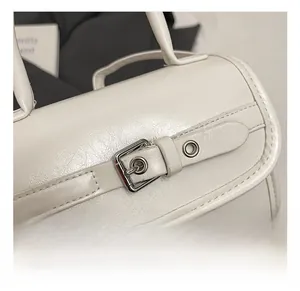 Detail of silver metal buckle closure on white textured patent leather handbag