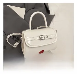 Detail view of white patent leather handbag featuring metallic buckle and top handle