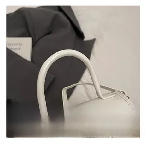 Detailed view of the sturdy round handle and fine stitching on the white patent leather bag