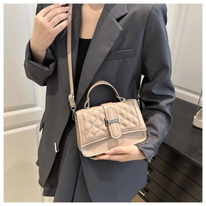 Chic beige quilted leather handbag with silver H-buckle detail worn by a model