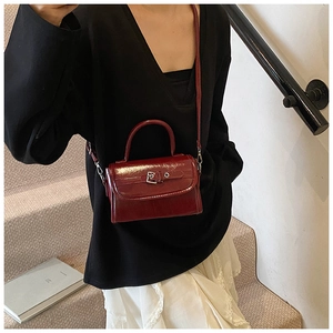 Detailed view of glossy burgundy patent leather mini square bag with silver metal buckle