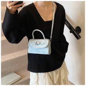 Close-up of a light blue mini crossbody bag featuring a vintage flap and buckle detail