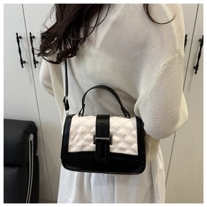 Sac bandoulière matelassé noir et blanc porté par un mannequin dans un décor moderne