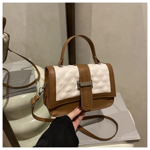Detail of white quilted flap and brown leather body with metallic turn-lock closure