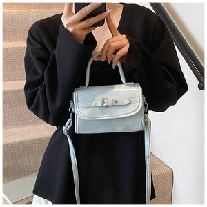Macro shot of light blue patent leather bag with metallic buckle and detachable strap