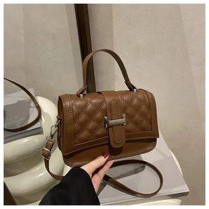 Detailed view of brown quilted PU leather handbag with silver twist lock and shoulder strap