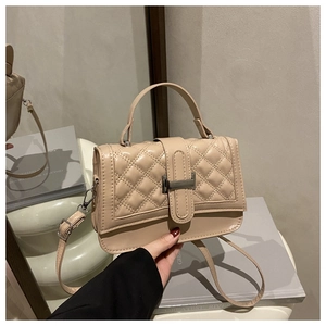 Detail of beige quilted crossbody bag with metal clasp and adjustable shoulder strap