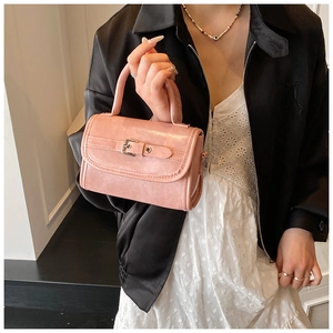 Detailed view of pink patent leather handbag with stylish metal buckle and top handle
