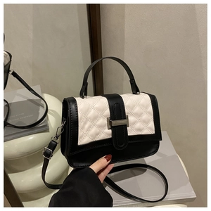Detail of black and white quilted crossbody bag with turn-lock and metal hardware