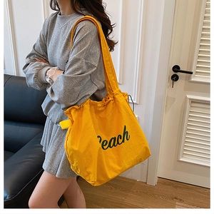 Close-up of bright yellow drawstring tote bag featuring Peach text and nylon texture
