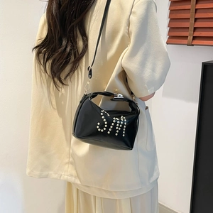 Sac fourre-tout noir minimaliste avec logo SM en perles porté à l'épaule du mannequin