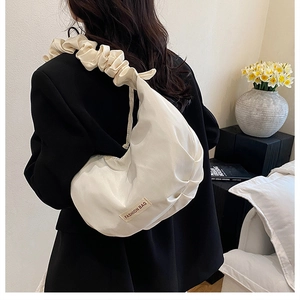 Détail de la bandoulière froncée beige et étiquette mode sur le sac hobo plissé